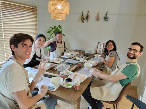 Five people prepare food at a table.