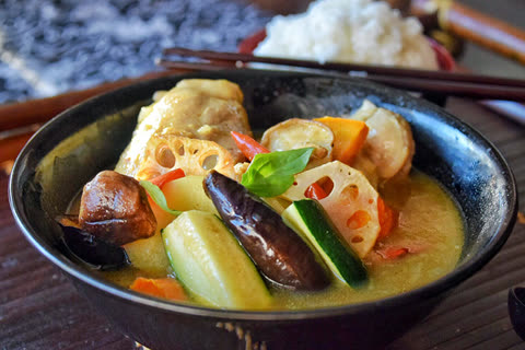 Chicken and vegetable stew in a black bowl.