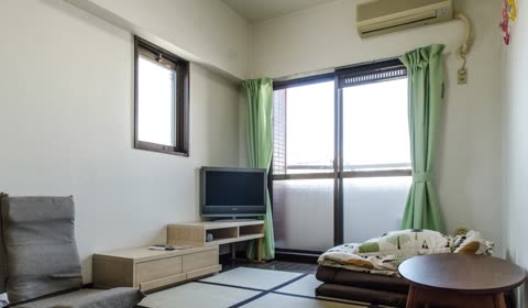 Apartment living room with futon bed, television, and small table.